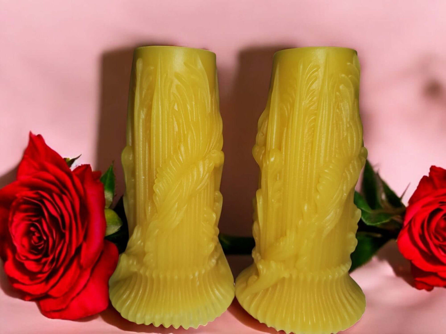 Sensual yellow massage candle sticks surrounded by red roses for intimate and erotic play.