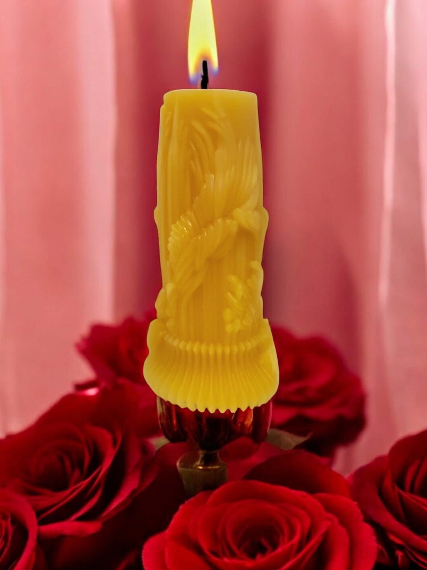 Yellow decorative candle burning surrounded by red roses, perfect for romantic settings and intimate moments.