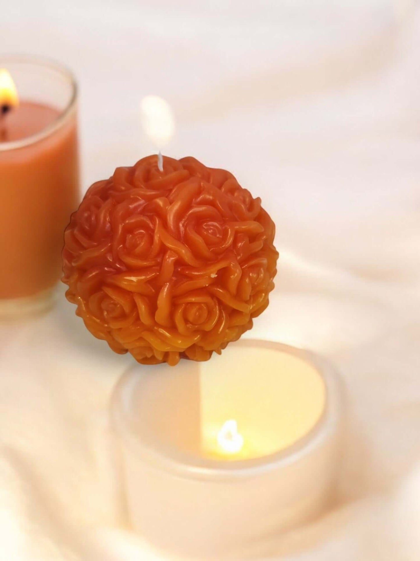 Rose-shaped massage candle, perfect for sensual play and relaxation, surrounded by lit candles on a soft surface.
