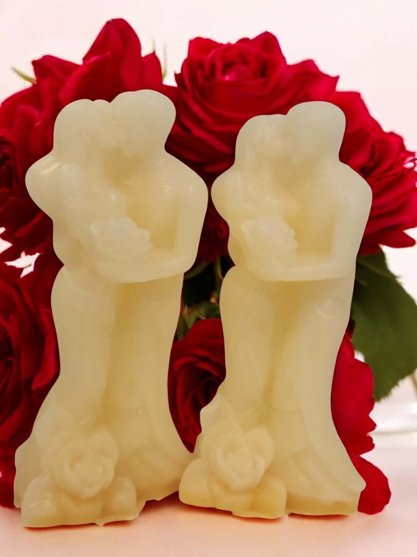 Couple cake candle figurines against a backdrop of romantic red roses, ideal for intimate moments.