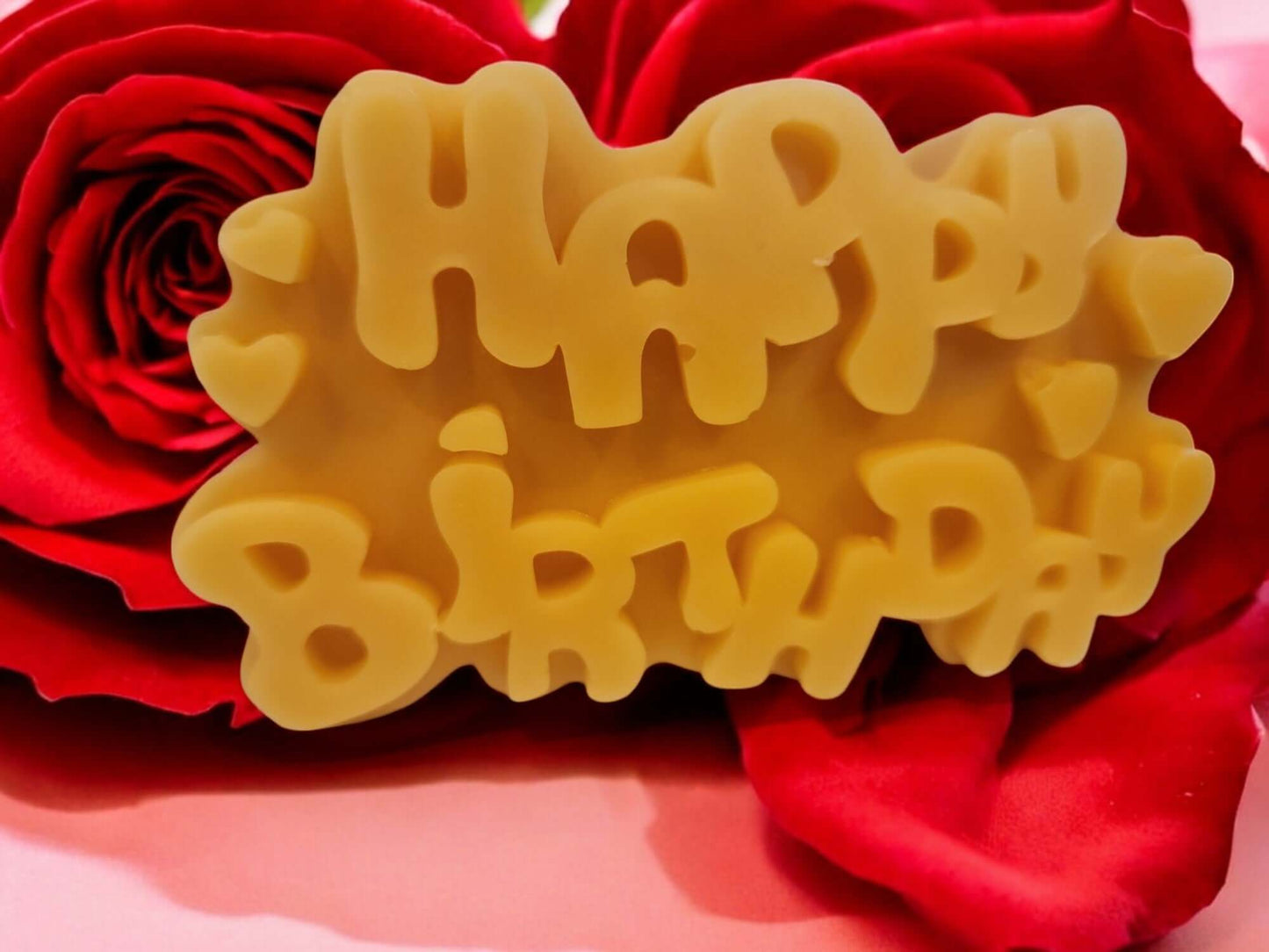 Happy Birthday candle displayed on red rose petals, perfect for celebrations and romantic occasions.