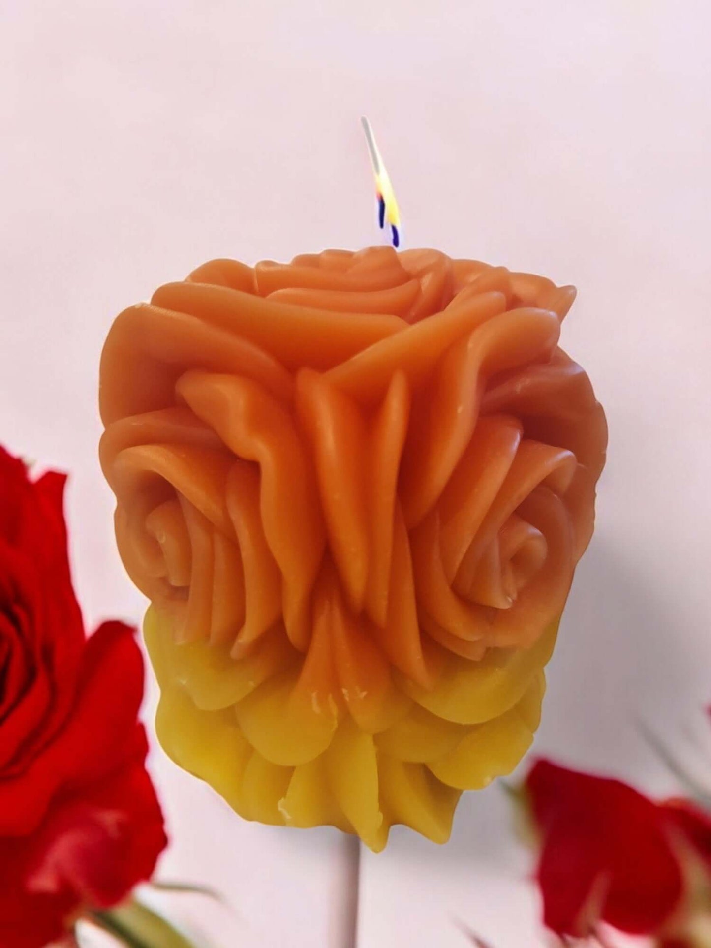 Sensual rose-shaped candle in warm orange and yellow hues, perfect for intimate massages and romantic settings.
