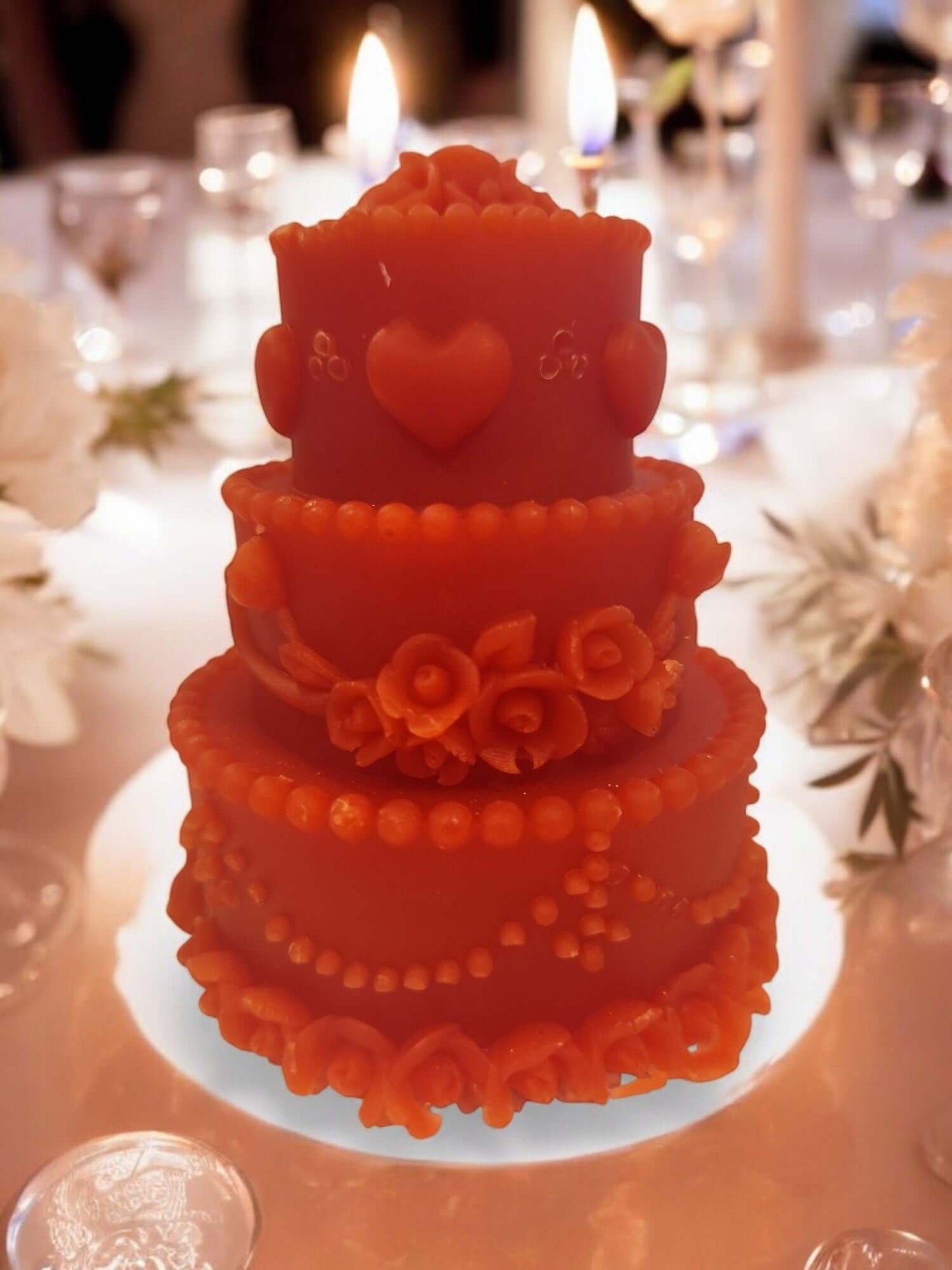 Decorative three-tiered orange candle with floral details, perfect for romantic settings and intimate occasions.