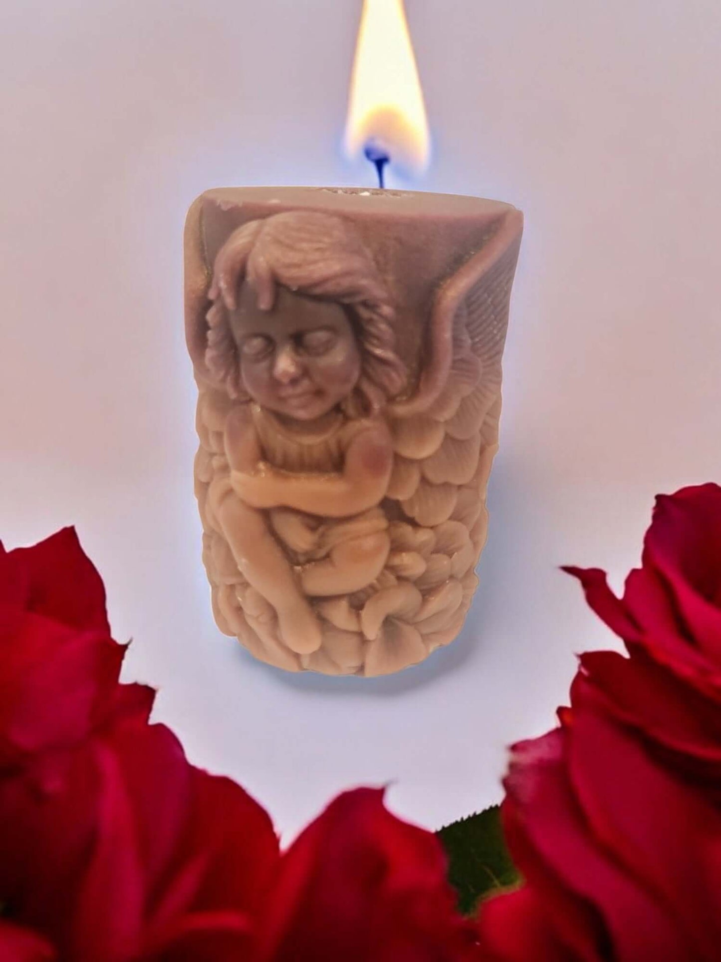 Angel Wing candle with a flickering flame, surrounded by red roses, ideal for sensual massages and romantic moments.