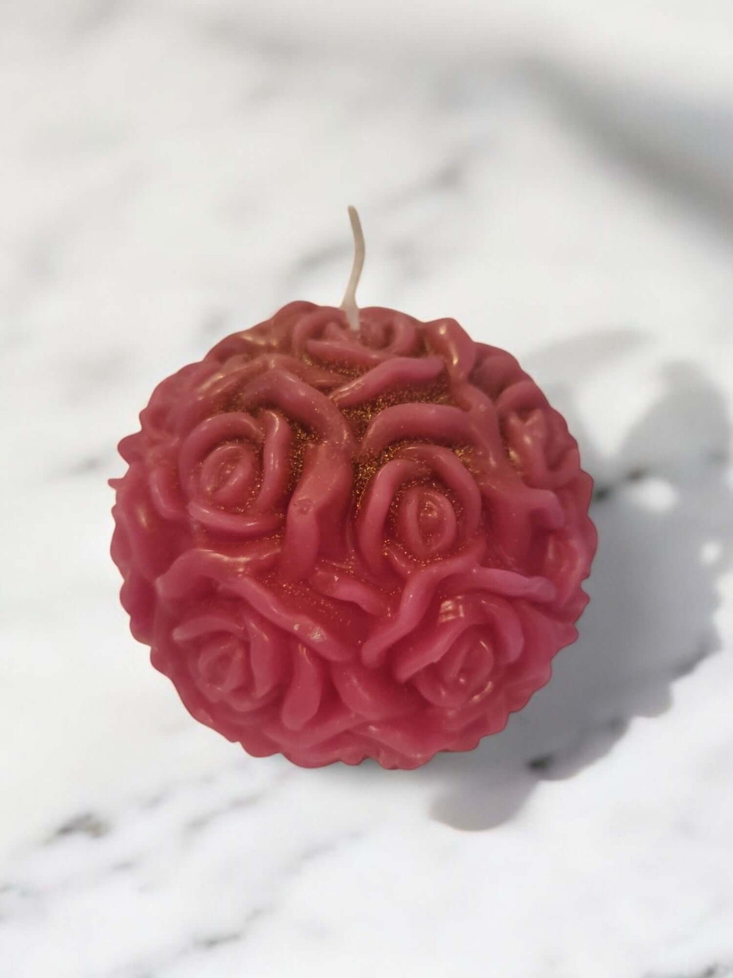 Rose-shaped pink massage candle on a marble surface, perfect for sensual intimacy and erotic play.
