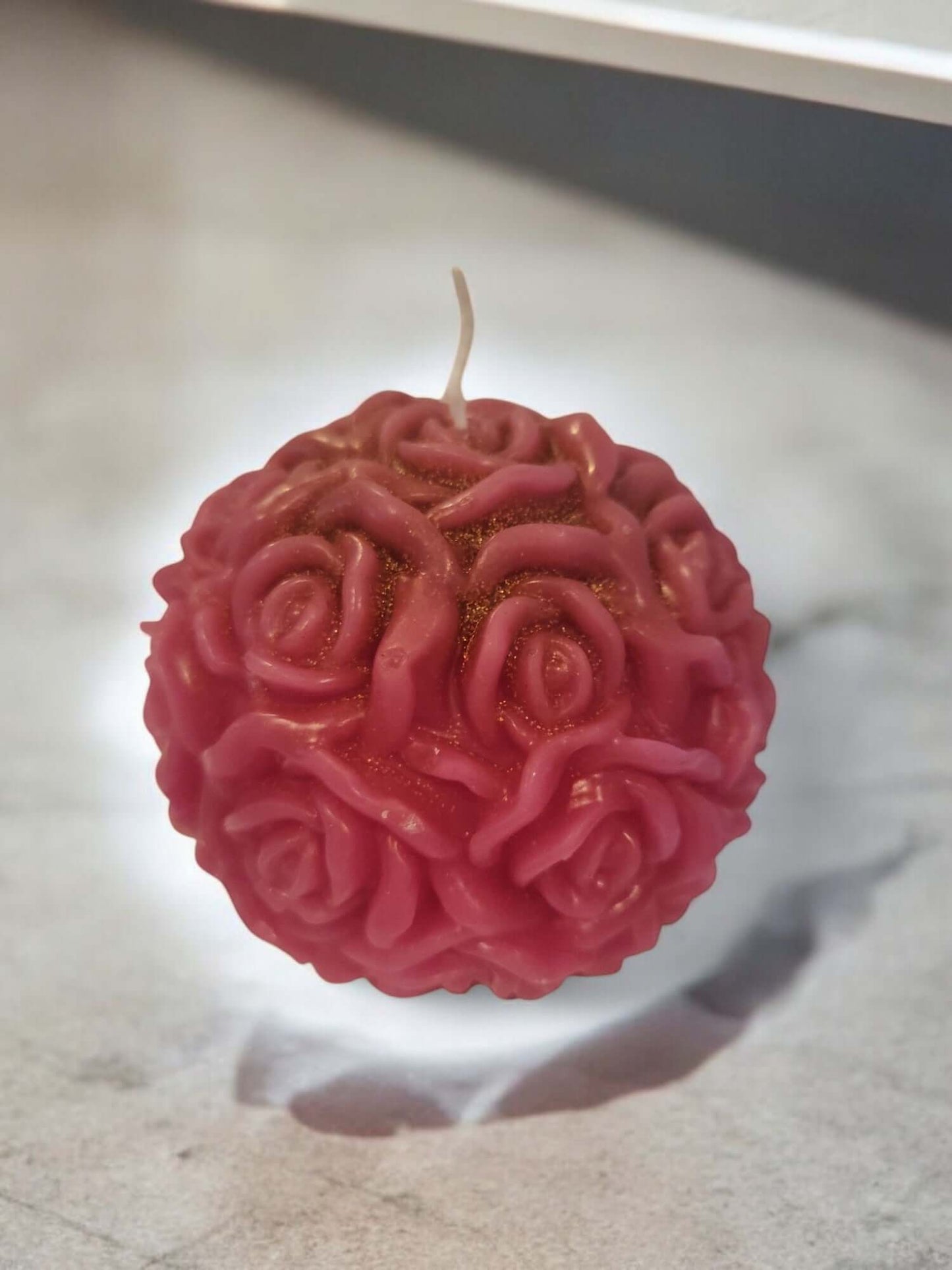 Decorative rose ball candle in pink, perfect for romantic mood lighting and sensual massage experiences.